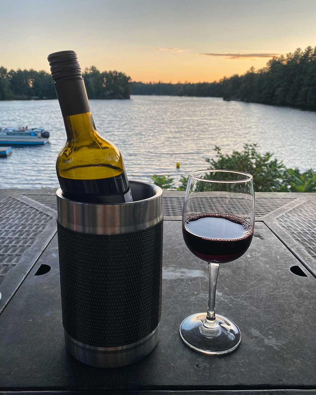 Red Wine in a Glass with bottle and a lake view in the background